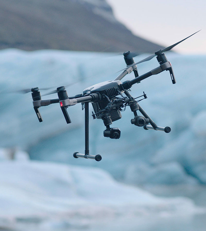 Drone flying over a snow patch, navigating difficult terrain as a metaphor for navigating evolving aviation regulations.